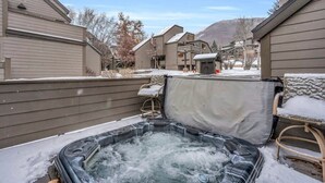 Ein Whirlpool in einem Garten mit überdachtem Bereich und einem Stuhl.