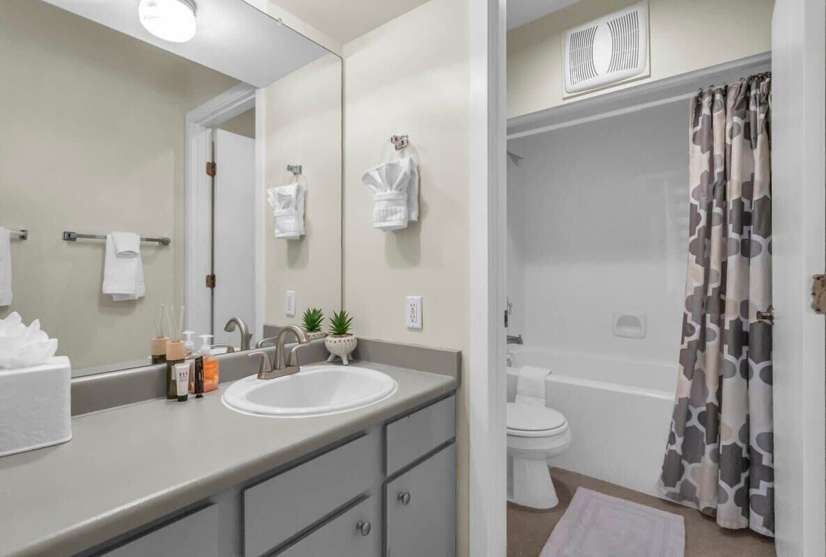 Une salle de bain moderne avec un grand miroir, un lavabo, des toilettes et un espace douche.