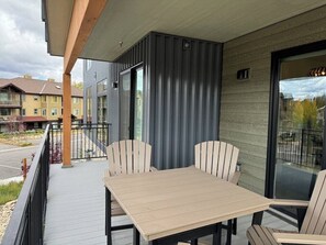 A balcony with a table and chairs, a railing, and a view of neighboring buildings.