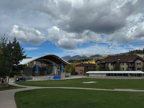 Ein modernes Gebäude mit gewölbtem Dach, umgeben von einer gepflegten Rasenfläche und einem Bergpanorama.