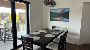 Un comedor con una mesa negra, seis sillas y un cuadro de un paisaje en la pared.
