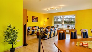 Une pièce aux murs jaune vif, avec un canapé, une table à manger et des chaises.