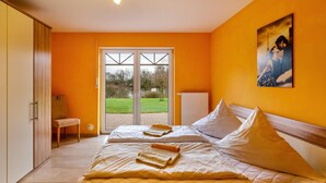 Une chambre d’hôtel avec deux lits, une vue sur l’extérieur depuis la porte et un tableau au mur.