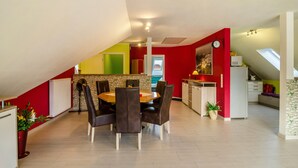 Un comedor con una mesa y sillas, una cocina al fondo y una pared roja.