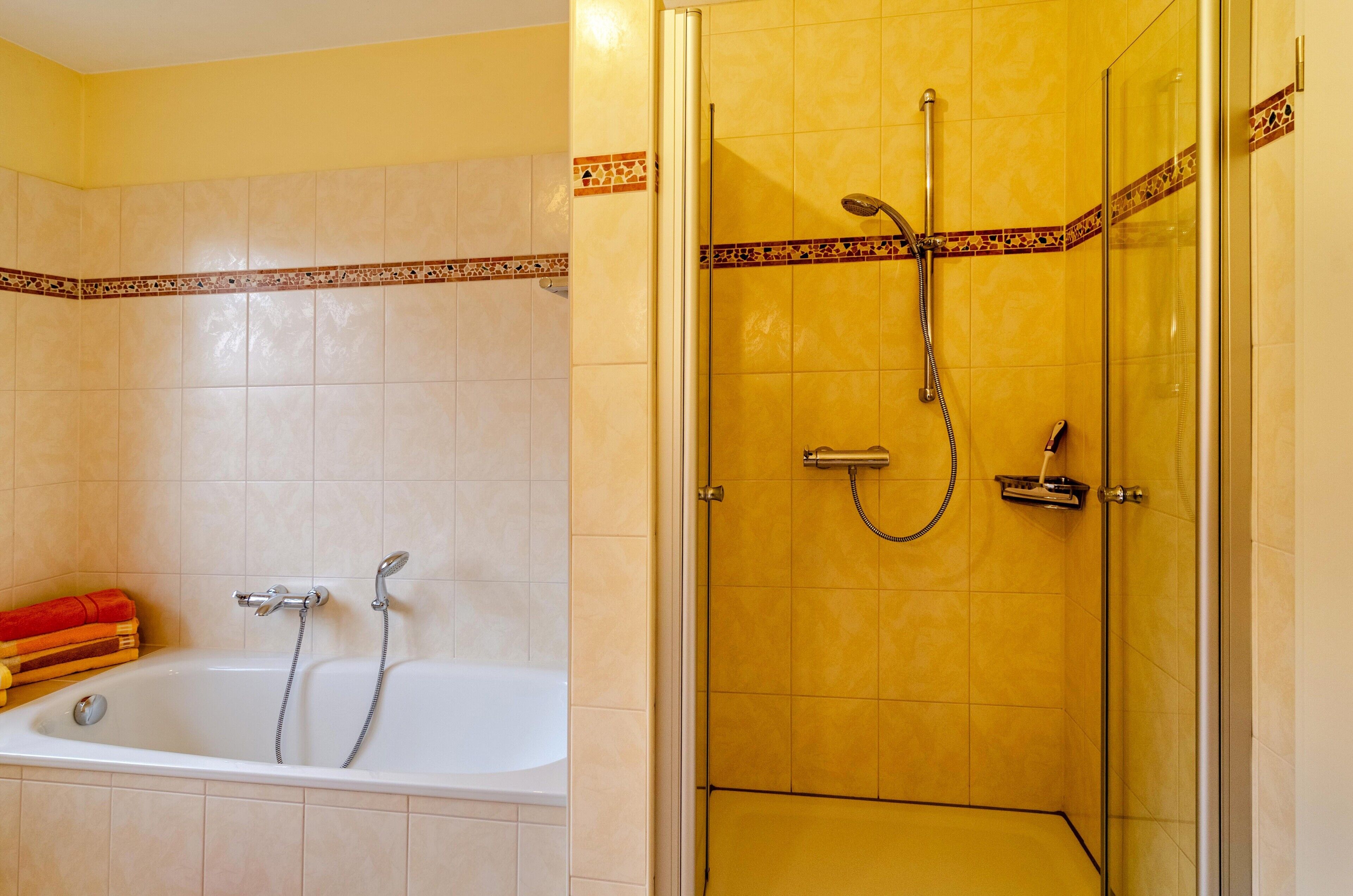 A bathroom with a bathtub, shower, and tiled walls.
