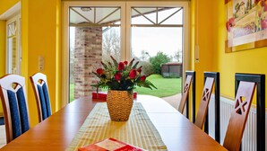 Une table à manger avec un livre, des chaises et un vase de fleurs.