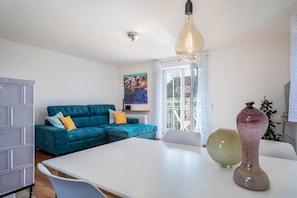 Un salon moderne avec un canapé de couleur turquoise, une table blanche et un grand vase.