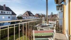 A balcony with a table and chairs, a railing, and a view of neighboring houses. - Apartment 'Windhager Seeblick' with Lake View, Balcony and Wi-Fi (Friedrichshafen)