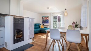 A modern kitchen with a built-in stove, a dining area with a white table and chairs, and a cozy living space with a teal sofa. - Apartment 'Windhager Seeblick' with Lake View, Balcony and Wi-Fi (Friedrichshafen)