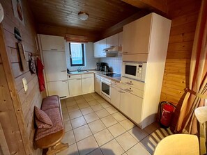 A compact kitchen with white cabinets, a built-in oven, a microwave, and a window above the sink.
