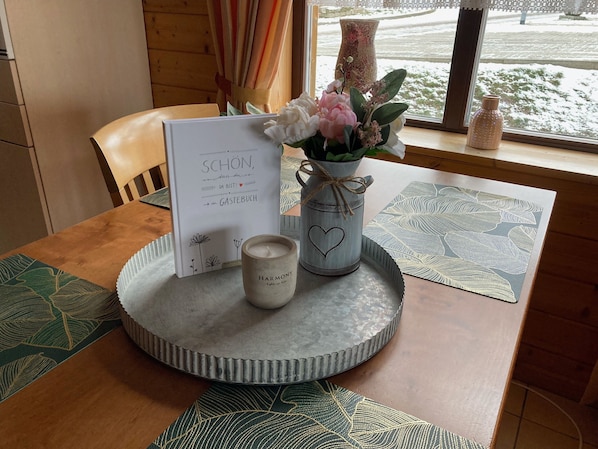 A table with a candle, a vase with flowers, a framed card, and a decorative tray.