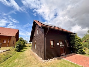 A wooden cabin with a sloped roof, a front door, and a small porch.