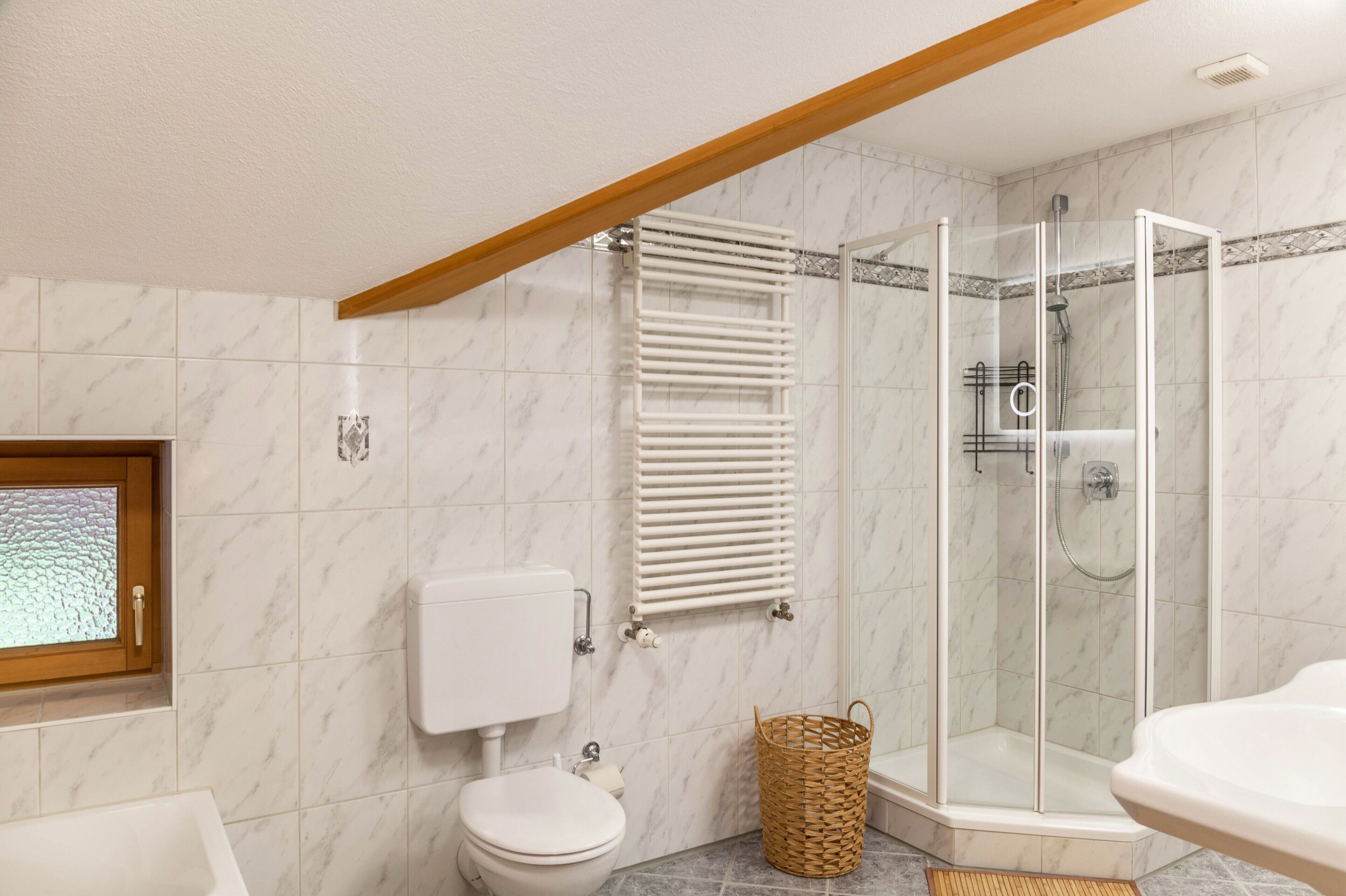 Un baño con inodoro, cabina de ducha, lavabo y ventana.
