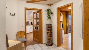 A hallway with wooden beams, a chair, a plant, and a stack of firewood. - Apartment "Mair - Sonnaufgang" with Mountain View, Shared Terrace & Wi-Fi (Halblech)