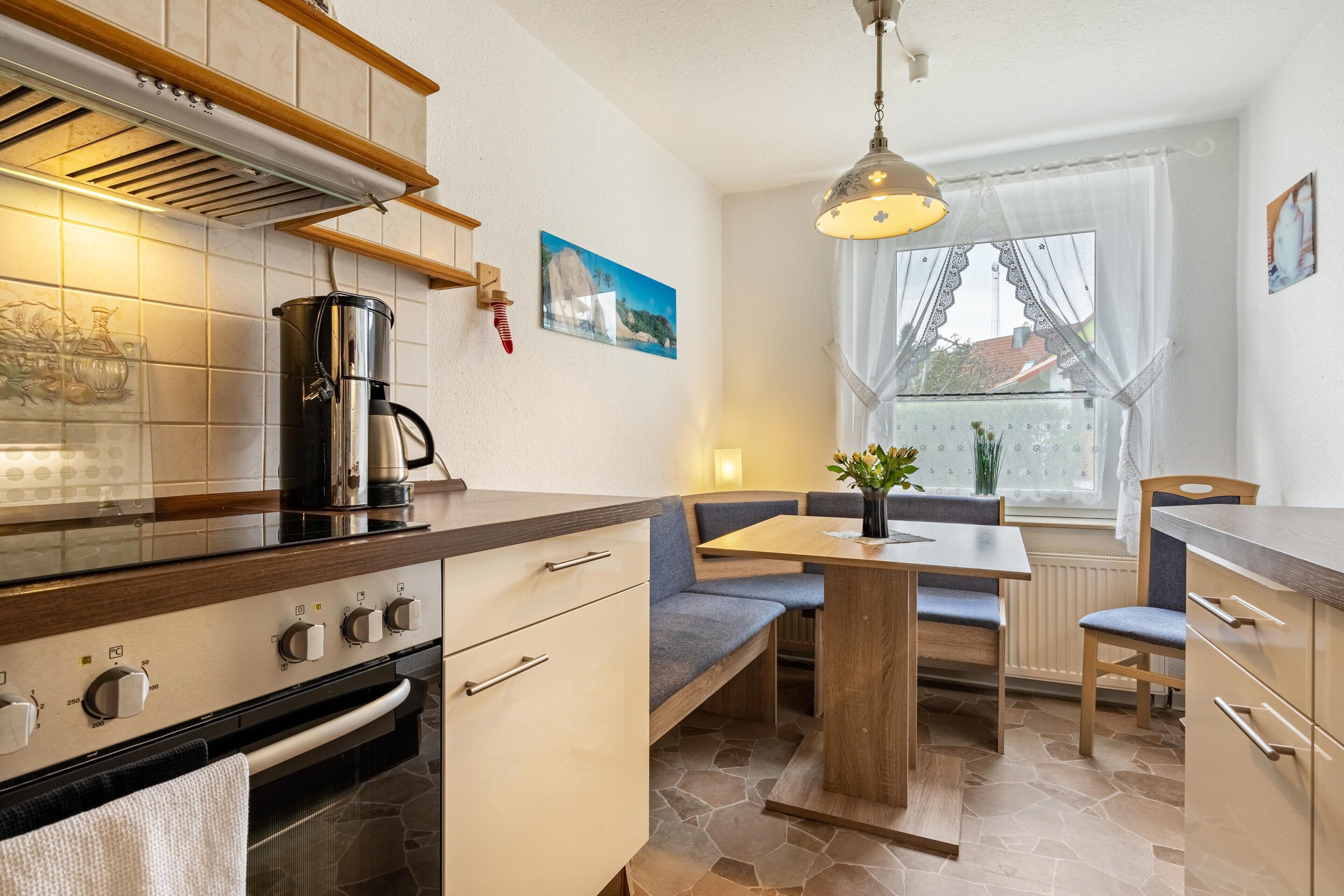 Una cocina compacta con estufa, horno y comedor con banco y mesa.