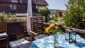 Eine Terrasse mit Tisch, Stühlen, einer Vase mit einem Sonnenblume und einer Laterne.