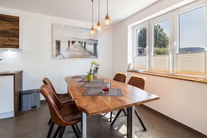 A dining area with a wooden table, brown chairs, a painting, and a window with blinds. - Apartment 'Helena' with Balcony and Wi-Fi (Öhningen)