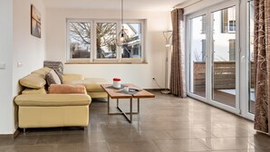 A modern living room with a sofa, a coffee table, and a large window. - Apartment 'Gertrud' with Lake View, Balcony and Wi-Fi (Öhningen)