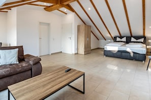 Ein modernes Schlafzimmer im Loft-Stil mit schrägem Dach, einer Couch, einem Bett und einem Holzschrank.