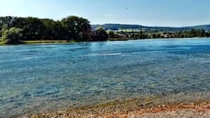 A river with clear water, a pebbly shore, and a forested area in the background. - Apartment 'Gertrud' with Lake View, Balcony and Wi-Fi (Öhningen)