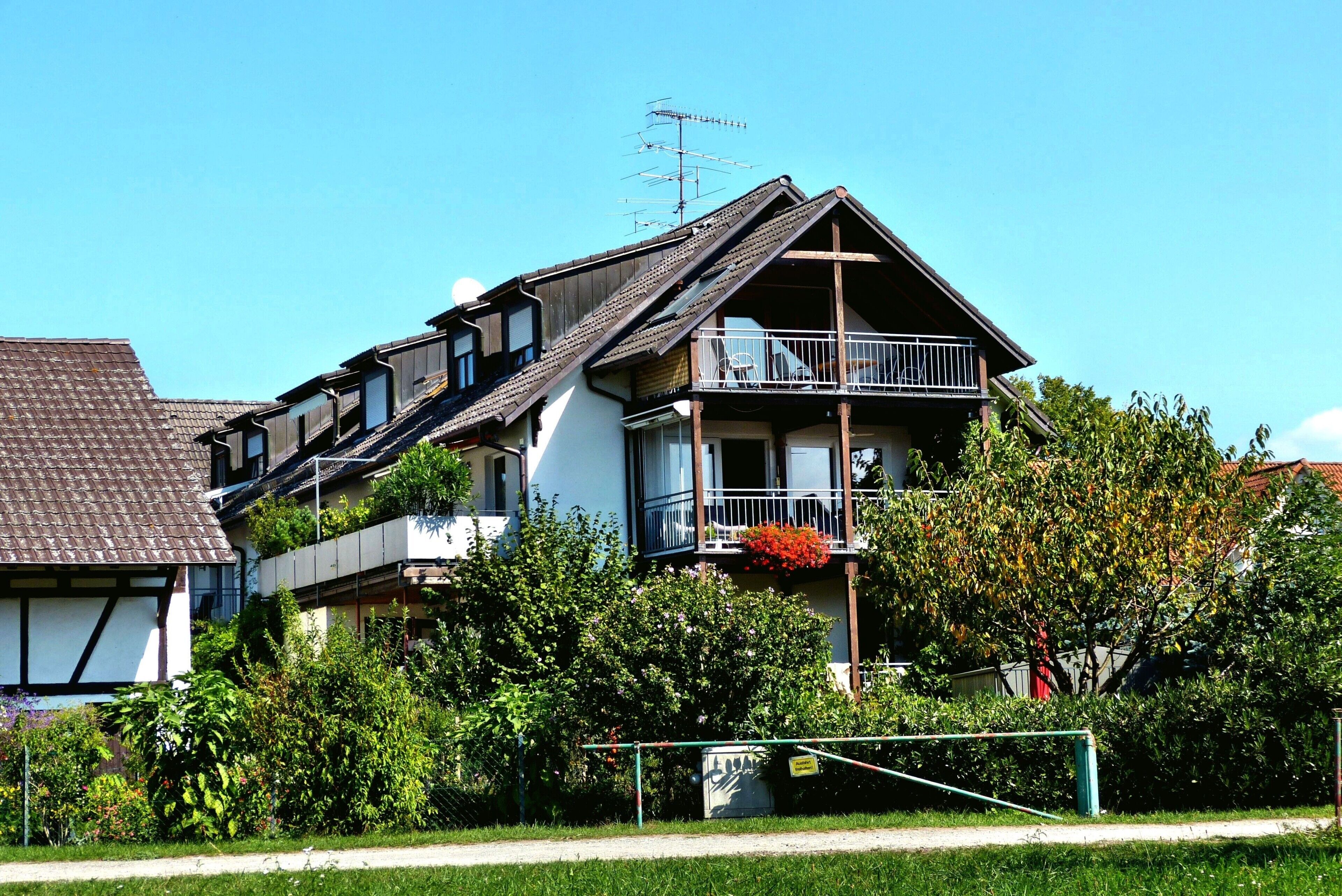 Un immeuble résidentiel à plusieurs étages, doté d’un balcon et entouré de verdure.