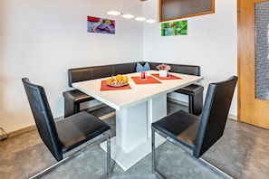 A conference room with a white table, black chairs, a red vase, and two framed pictures on the wall.