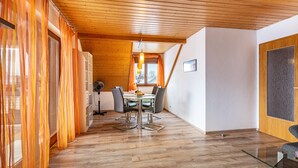 A modern interior with a wooden ceiling, a dining area with a glass table, and a view through a window with curtains. - Apartment 'Anca' with Lake View, Balcony and Wi-Fi (Öhningen)