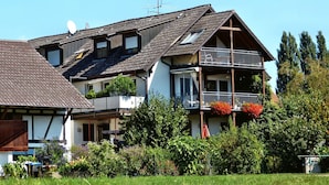 A multi-story building with a sloped roof, balconies, and satellite dishes. - Apartment 'Anca' with Lake View, Balcony and Wi-Fi (Öhningen)