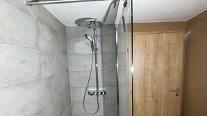 Une douche équipée d’un pommeau de douche à main, d’un robinet mural et d’un panneau de commande.