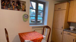 Une petite cuisine avec une table, des chaises, une fenêtre et des armoires en bois.