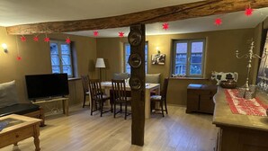 Una sala de estar acogedora con televisor, muebles de madera, una mesa de comedor y chimenea.