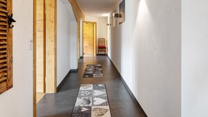 A hallway with wooden doors, a patterned rug, and a chair.