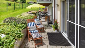 A patio with outdoor furniture, a yellow umbrella, and a view of a house in the background.