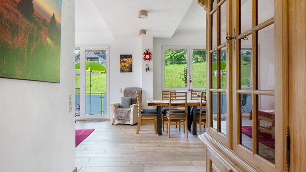 A dining area with a table and chairs, a view of the outdoors, and a painting on the wall. - Apartment 'Ulrich' with Mountain View, Shared Terrace and Wi-Fi (Oberried-Hofsgrund)