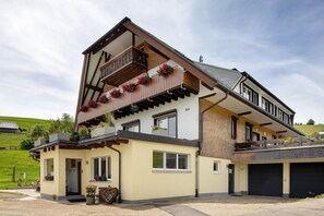 A two-story building with a balcony, a garage, and a small entrance. - Apartment 'Ulrich' with Mountain View, Shared Terrace and Wi-Fi (Oberried-Hofsgrund)