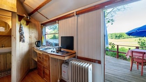 Une cuisine rustique, située dans une cabane en bois, avec une fenêtre, un radiateur et une table à l’extérieur.