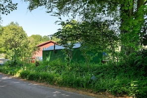 A green building with a red roof, surrounded by dense greenery and trees.