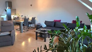 A modern living room with a dining area, a sofa, a coffee table, and a plant. - Holiday Apartment "Lampl Haus" with Wi-Fi (Steindorf)