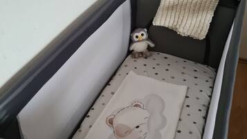 Ein Babybett mit sternenmusternder Matratze, einem Bären-Kissen und einer kleinen Stoff-Eule.
