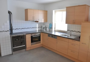 A kitchen with a stove, oven, dishwasher, and wooden cabinets.