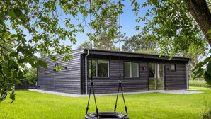 Et moderne hus med en gyngestol hængende i et træ.