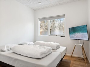 A modern bedroom with a bed, a TV, and a window with a view of trees.