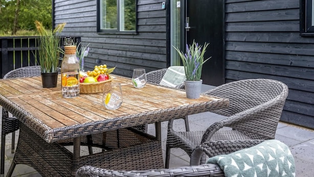 En træterrasse med fletmøbler, en frugtkurv og plantekasser.