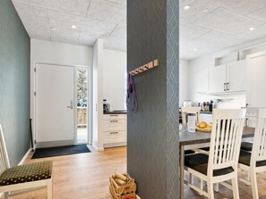 A modern kitchen with white cabinets, a wooden dining table, and a bench.