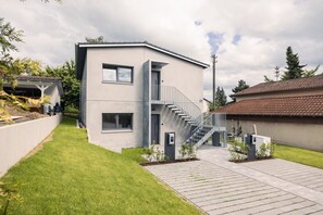 A modern two-story house with a staircase, a small garden, and a paved driveway.