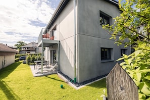 Une maison moderne à deux étages, dotée d’un balcon, d’une pelouse bien entretenue et d’une clôture en bois.