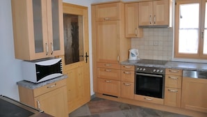 Una cocina con gabinetes de madera, estufa, horno y ventana.