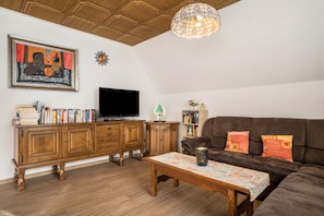 Un salon comprenant un meuble en bois, un téléviseur, un canapé et une table à motifs.