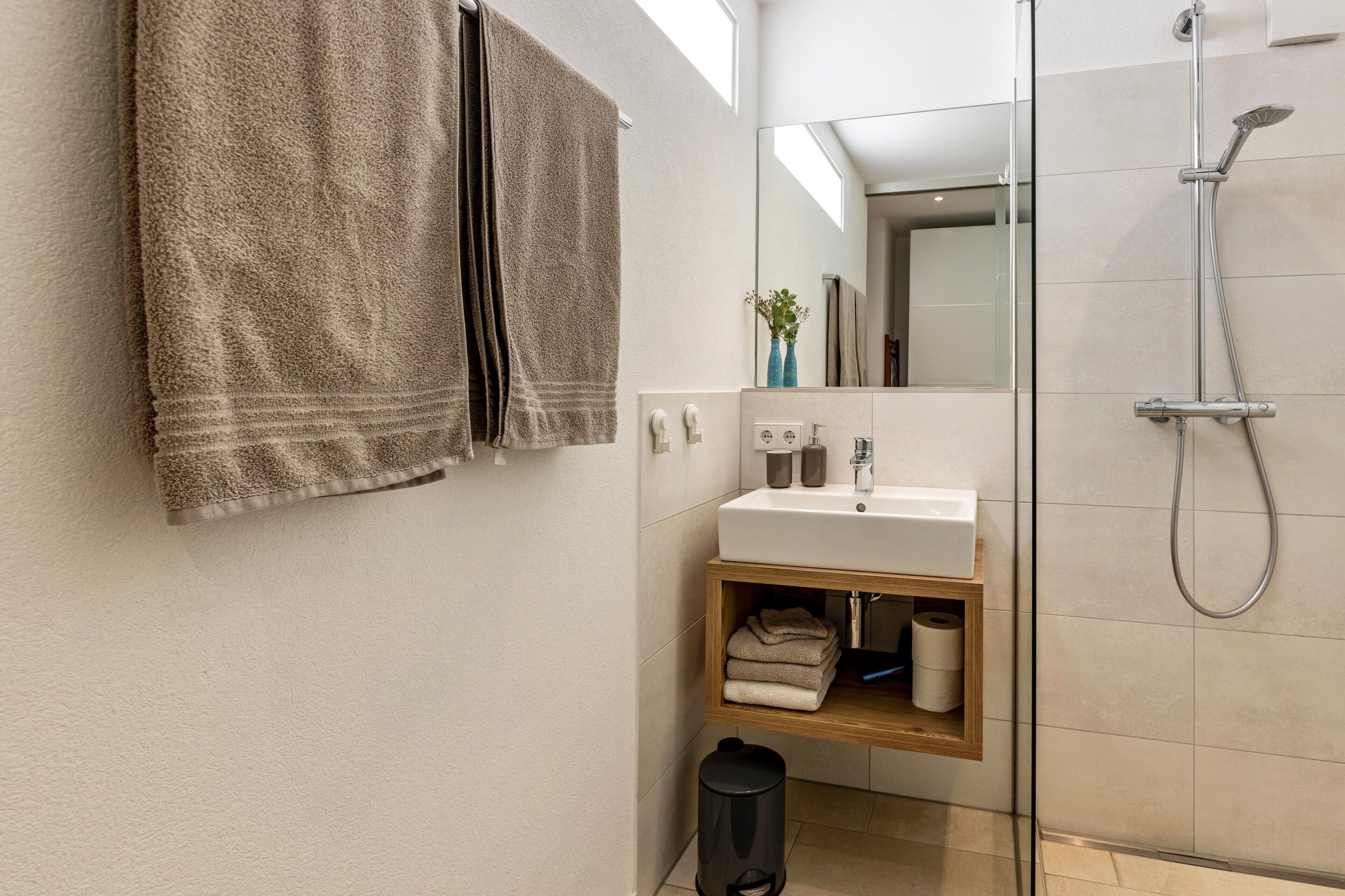 Un baño moderno con ducha, lavamanos, espejo y toallero.