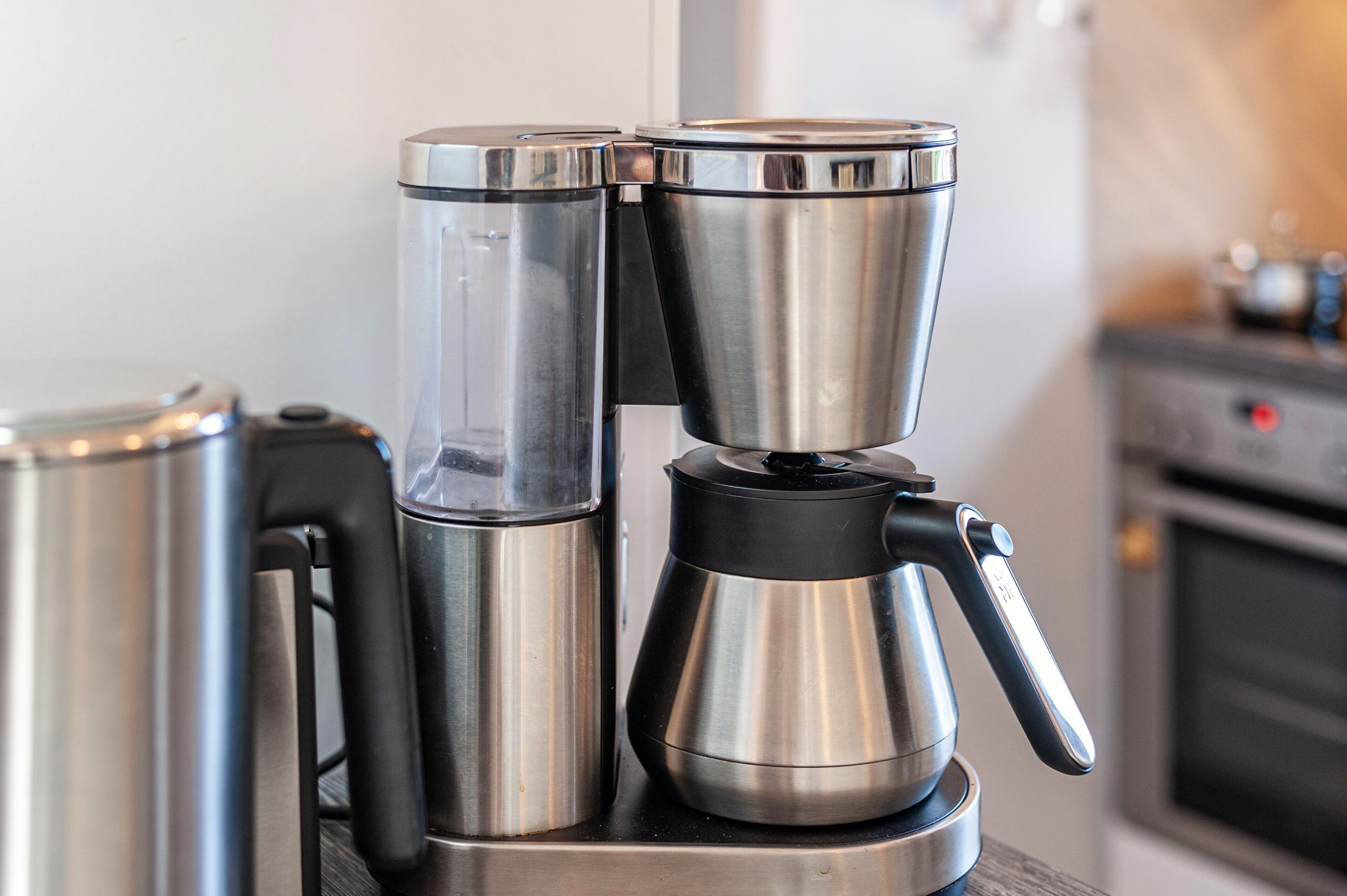 En kaffemaskine med drypbakke og vandbeholder på en køkkenbordplade.